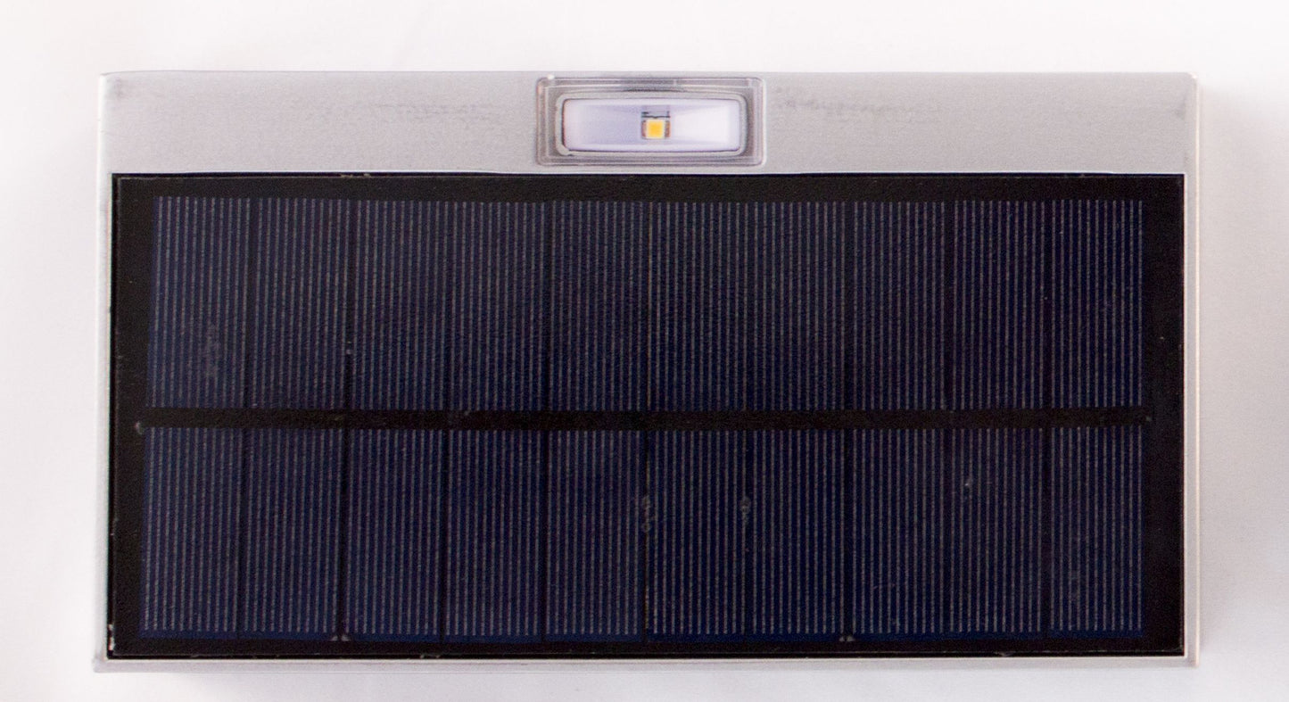 A rectangular silver LED up/down solar wall light with a solar panel on top and built-in LEDs.