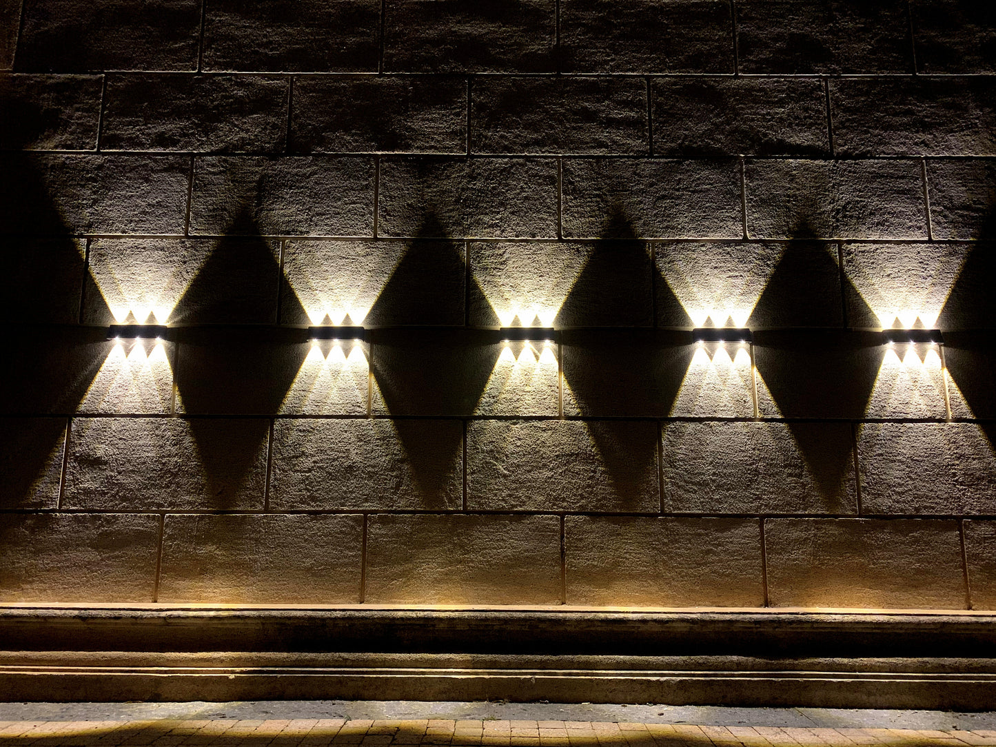 Black LED up/down solar wall light fixture with a solar panel on the front shown mounted on a wall