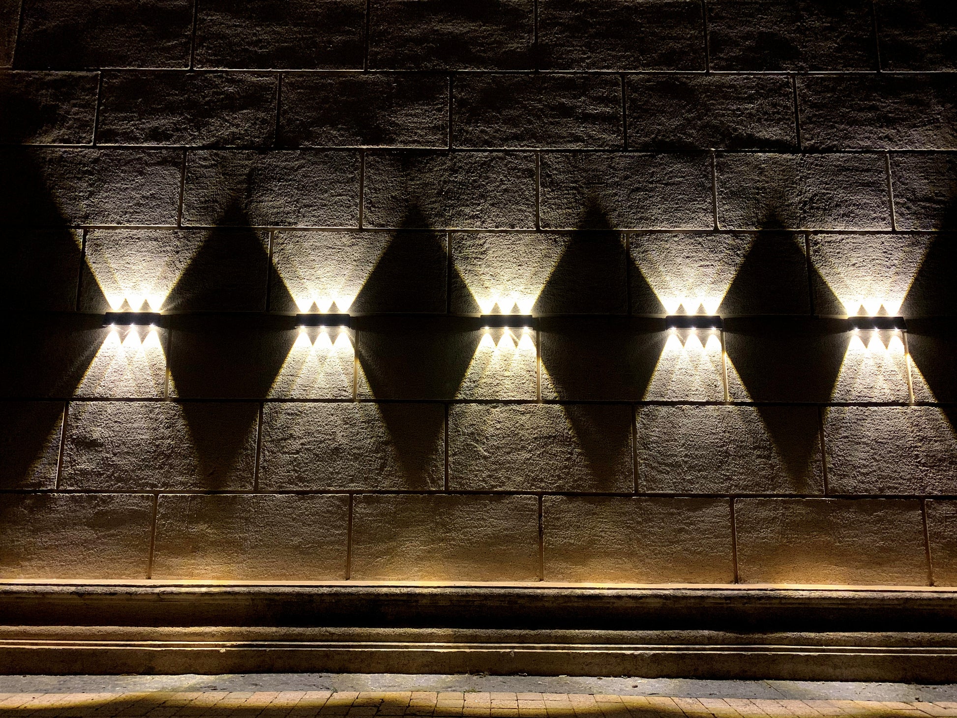 Black LED up/down solar wall light fixture with a solar panel on the front shown mounted on a wall